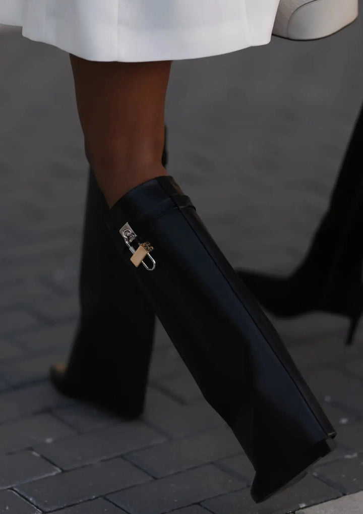 Contemporary women's glossy black boots, knee-high, with a striking sculptural wedge.
