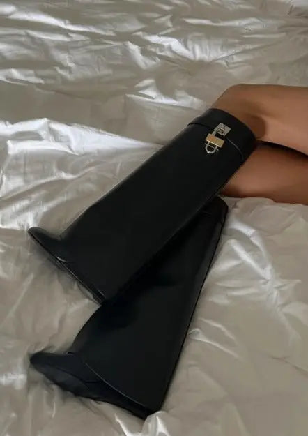 Fashion-forward women's wedge boots, glossy black, knee-high, sculptural style.