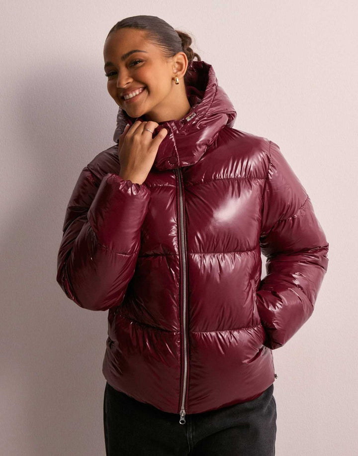 Women's warm winter outerwear: a stylish, shiny quilted jacket with a versatile hood.