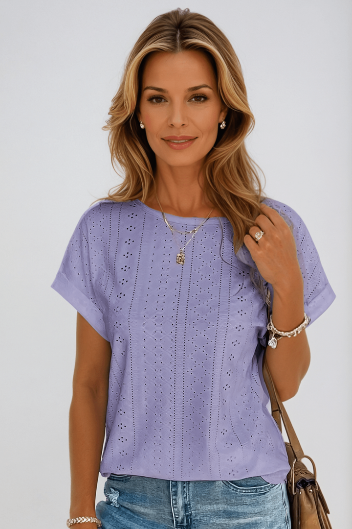 Comfy women's eyelet blouse featuring a round neck & short sleeves. Flowy design for elegant summer style.