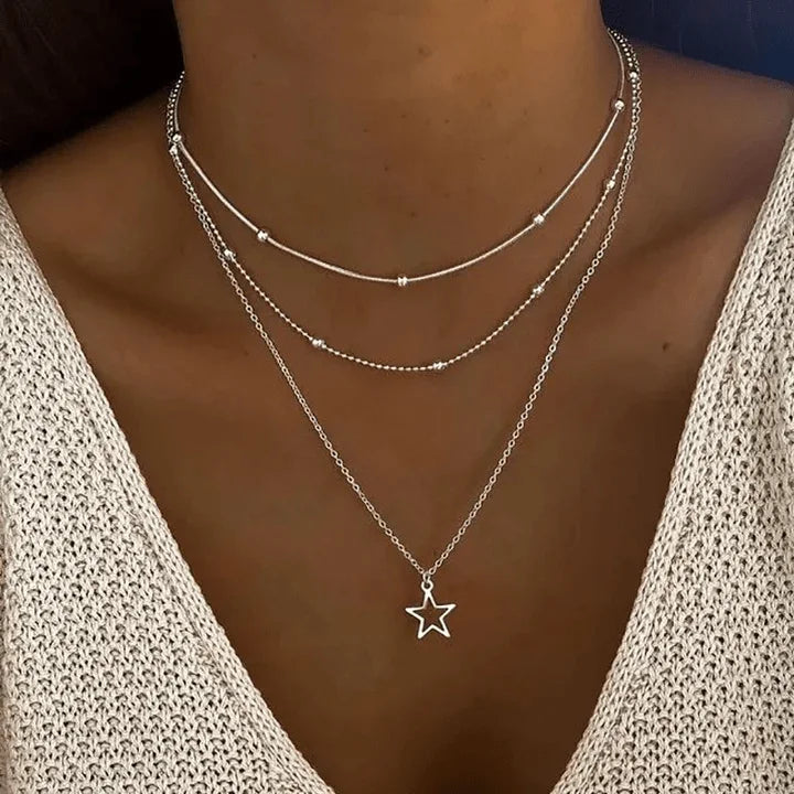 Women's silver layered necklace featuring a delicate beaded chain and star pendant, a fashionable jewelry accessory.