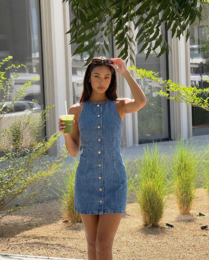 Stylish women's sleeveless mini dress with button front detail, ideal for a modern daytime summer outfit.