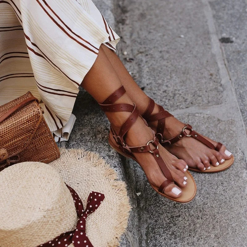 Detailed women's snake print gladiator sandals with secure ankle wrap and flat sole, ideal summer footwear.
