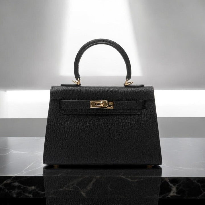 Women's structured top handle handbag with elegant gold lock. Perfect day-to-evening fashion accessory.