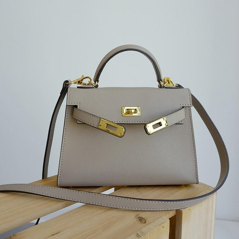 Classic women's top handle bag, structured silhouette, adorned with a shining gold lock. Essential accessory.