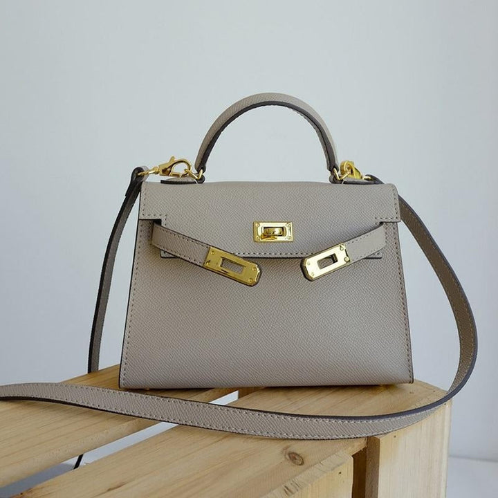 Classic women's top handle bag, structured silhouette, adorned with a shining gold lock. Essential accessory.
