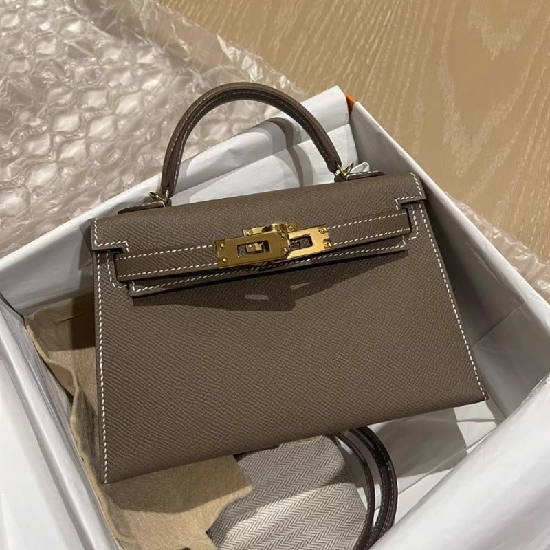 Functional and elegant women's structured handbag. Features a top handle and a gleaming gold lock.