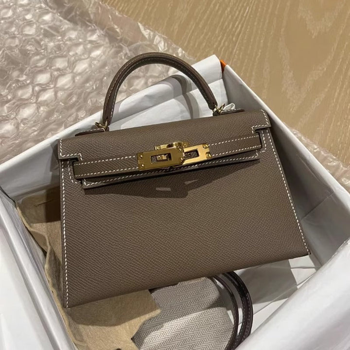 Functional and elegant women's structured handbag. Features a top handle and a gleaming gold lock.