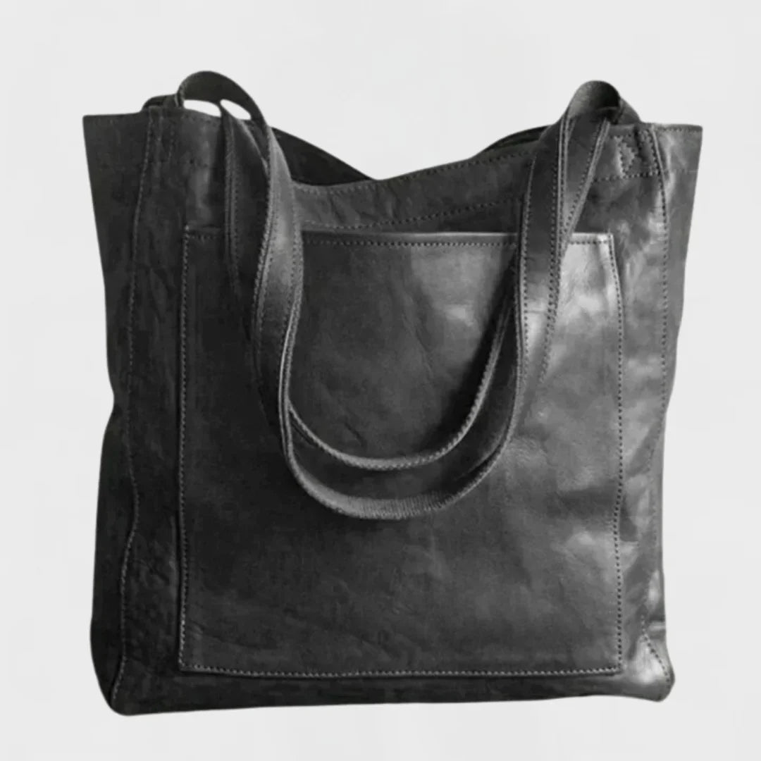 Close-up of the versatile black leather tote bag, highlighting its convenient front pocket and sturdy design.
