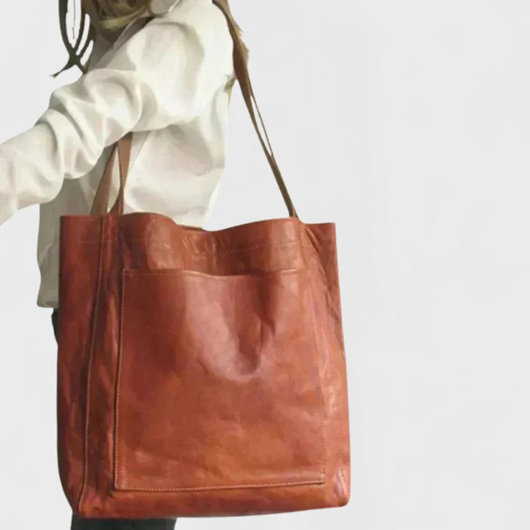 Woman carrying a sleek black leather tote bag with front pocket, ideal for work or casual outings.