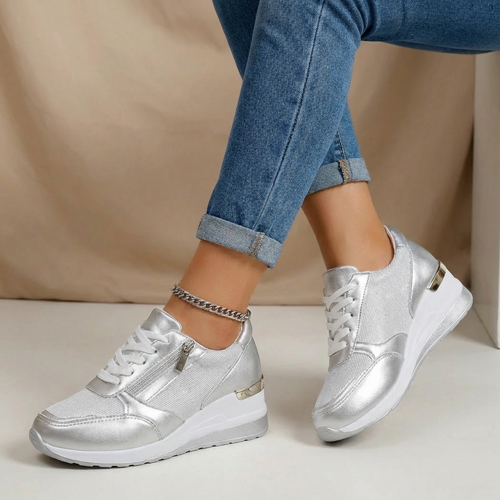 Silver women's chic wedge sneakers, designed for comfort and fashion, with a supportive lift and side zip.