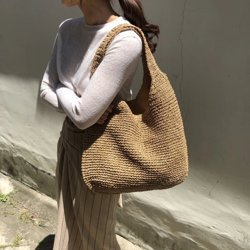Stylish woven straw hobo bag for women, ideal as a casual summer shoulder bag or beach tote.