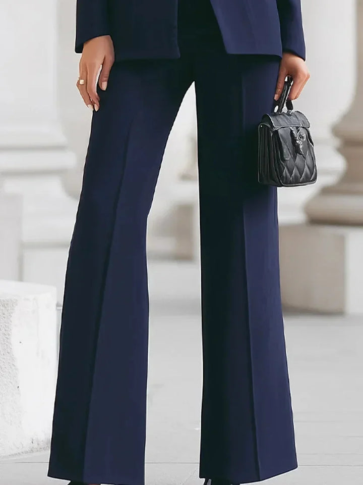 Woman wearing a stylish denim tailored jacket & flare trousers set, showcasing the modern silhouette.
