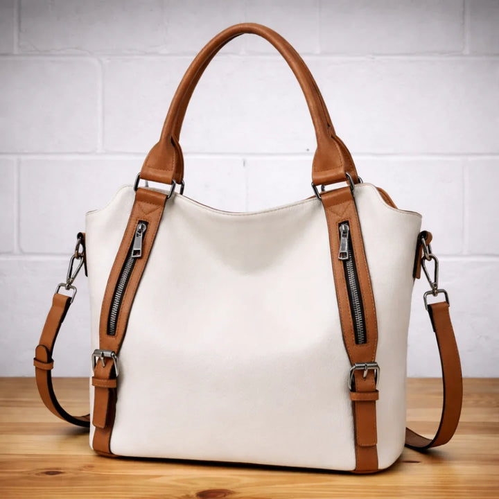 Close-up of tan faux-leather slouchy bag, highlighting material texture & dual zipper details.