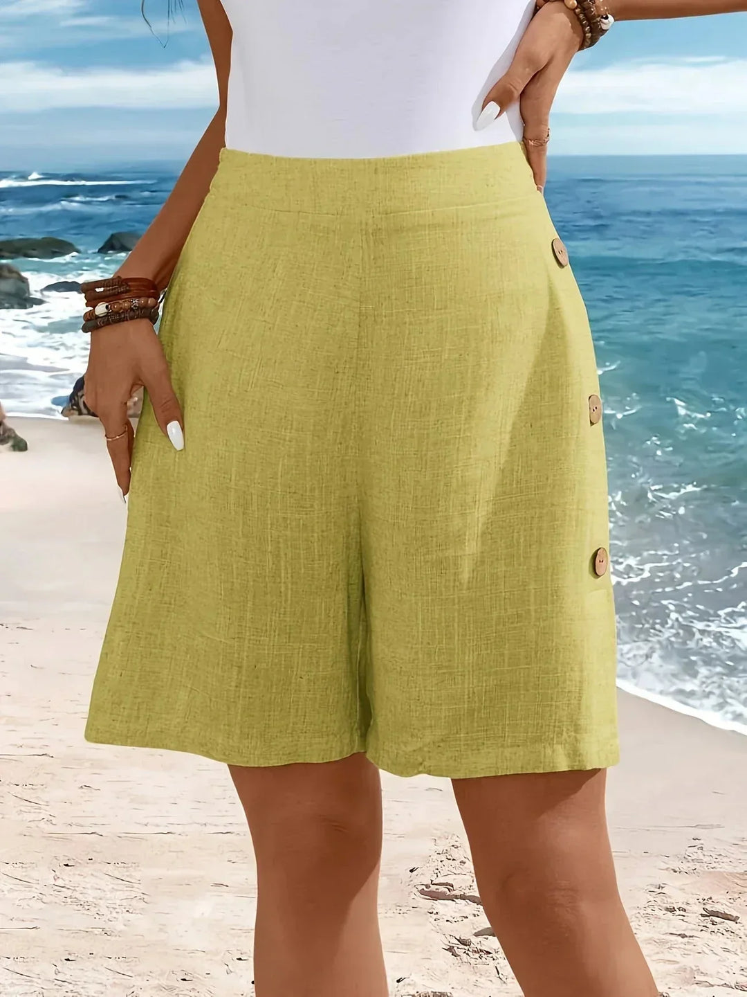 Model showcases women's high-waisted wide-leg shorts with textured fabric & stylish side button details. Summer casual.