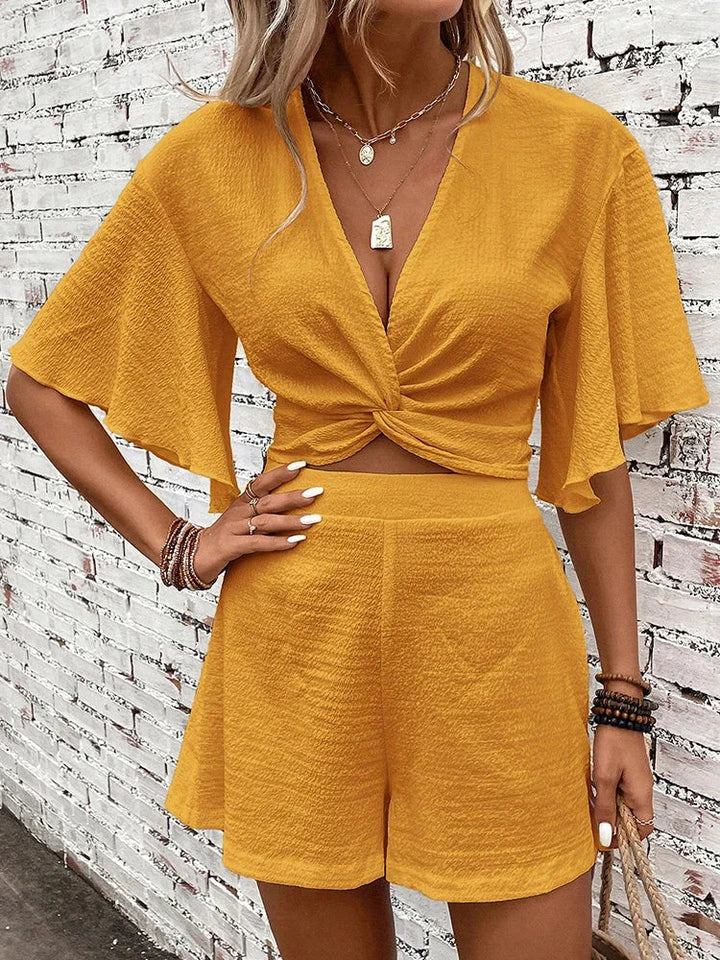 Stylish women's V-neck crop top with flutter sleeves, part of a textured two-piece summer shorts set.