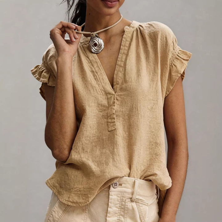 Chic women's V-neck blouse featuring ruffle cap sleeves & button placket. Relaxed fit summer top.