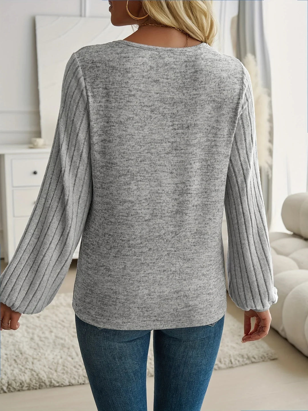 Close-up of women's V-neck sweater showing unique lantern sleeves & ribbed cuffs. A modern knit top.