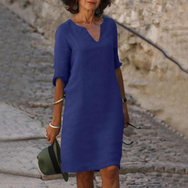 Close-up of the V-neck detail on a women's midi shift dress with 3/4 sleeves.