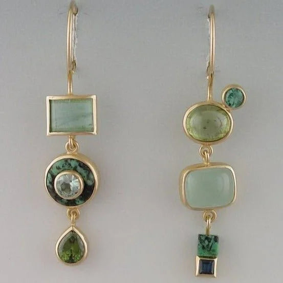Women's vintage gold tone asymmetric dangle earrings with striking green gems, perfect for a statement.