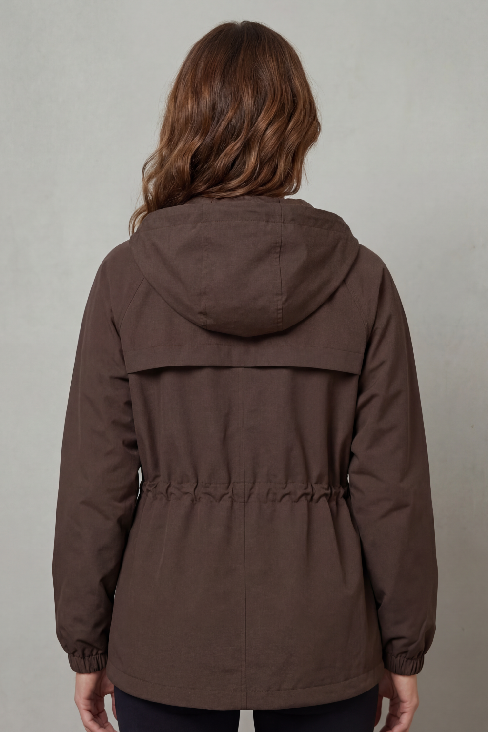Woman wearing a waterproof utility rain jacket with drawstring, ready for any weather.
