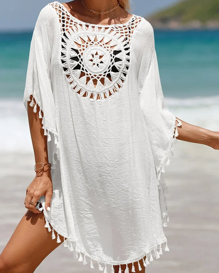 Boho mini beach cover-up featuring intricate crochet yoke and playful tasseled hem for stylish swimwear.