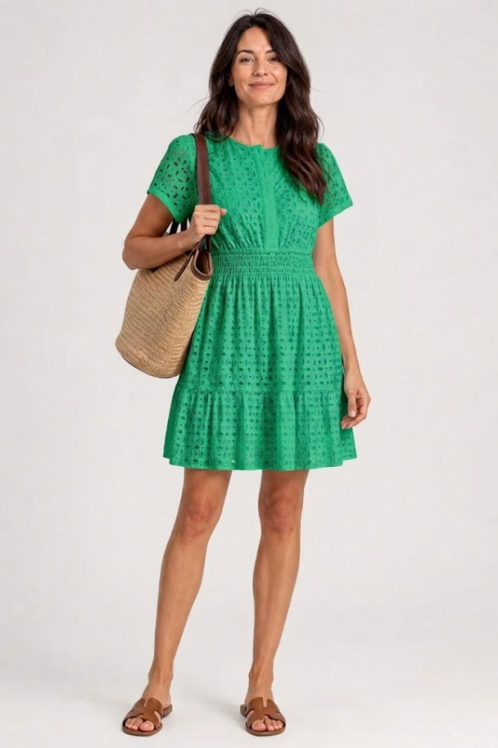 Woman enjoying summer in a casual green eyelet mini dress with flutter sleeves, a chic day dress.