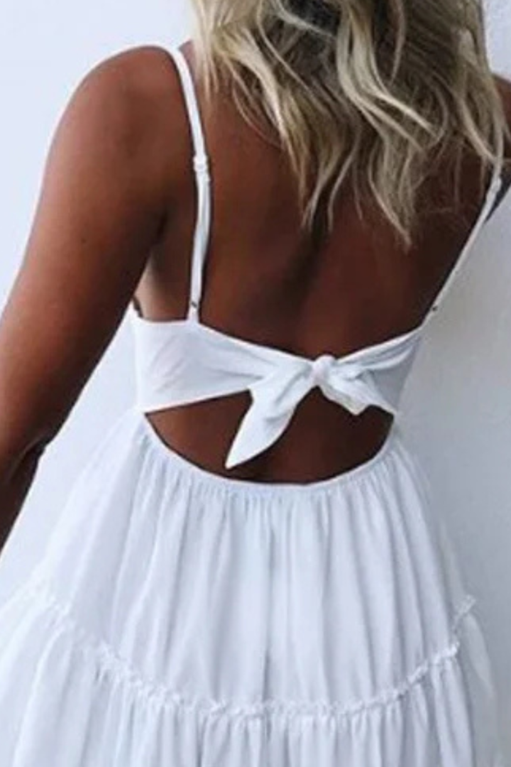 Holiday-ready white lace mini dress for women. Summer outfit with a v-neck, open back, and tiered skirt design.