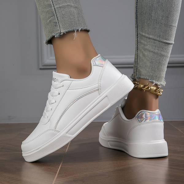 Close-up of white women's trainers showcasing elegant metallic sheen accents and durable lace-up design.