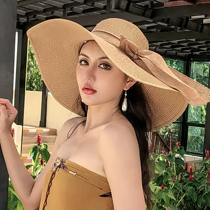 Women's wide brim straw sun hat with elegant bow detail, perfect for beach days.