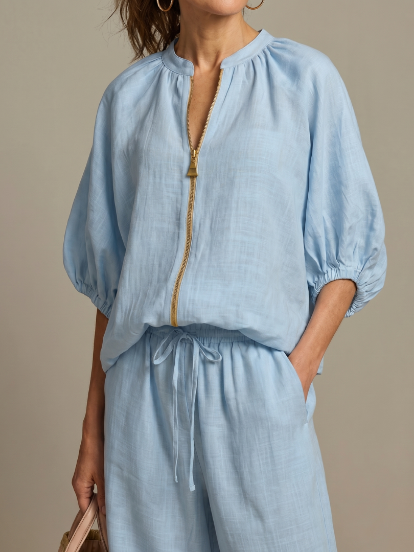 Elegant wide leg pants paired with a zip front blouson top, a versatile women's two-piece set.