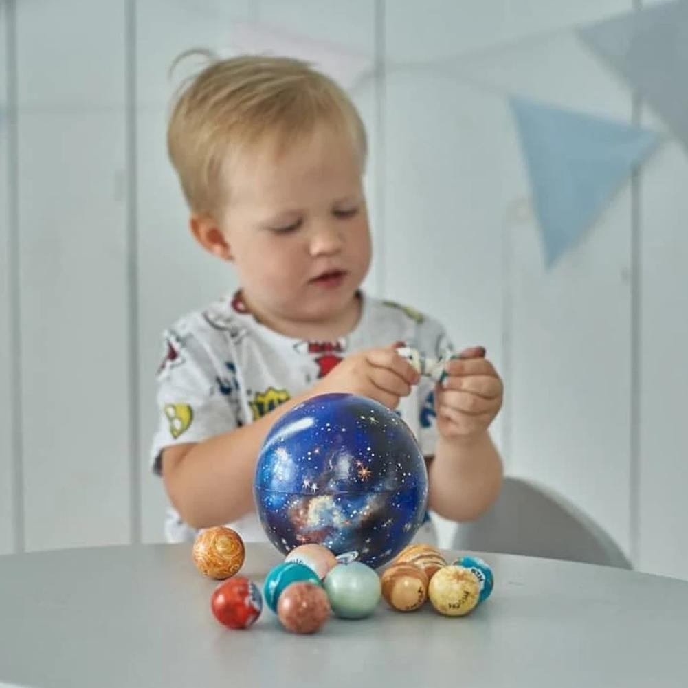 Child's hands playing with a wooden solar system planet set, promoting STEM learning