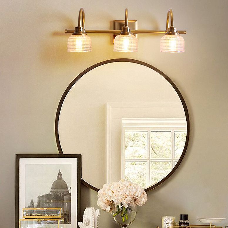 Antique brass indoor wall lamp with a sophisticated clear glass shade, hardwired for elegance.